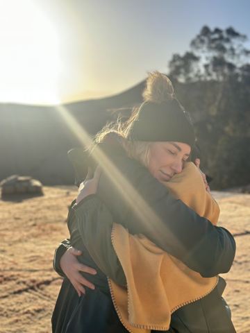 Two ASRI community members embracing in warm outdoor light